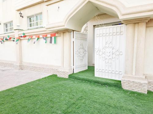 a white gate in a house with green grass at HARF22-02 Peaceful 2BR in Abu Dhabi city in Abu Dhabi