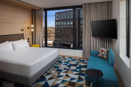 苏福尔斯Canopy By Hilton Sioux Falls Downtown的酒店客房设有床、沙发和窗户。