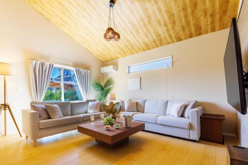 a living room with a couch and a table at YANBARU Villa 葵扇-KISEN- in Motobu