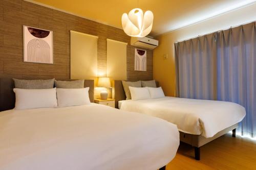 two beds in a hotel room with two beds at YANBARU Villa 葵扇-KISEN- in Motobu