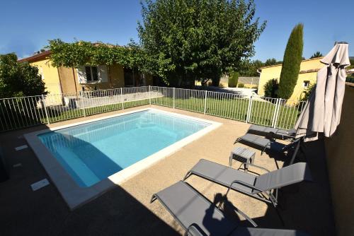 une piscine avec deux chaises et un parasol dans l'établissement La Bastide de Laura, à LʼIsle-sur-la-Sorgue