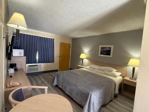 a hotel room with a bed and a table at Pine Needles Inn in Mount Shasta