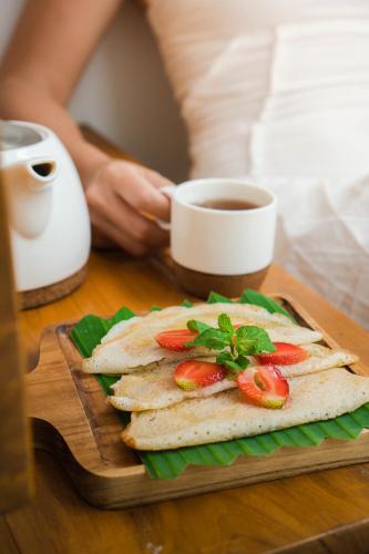 a sandwich on a cutting board with a cup of coffee at Tannari Villa Ubud in Ubud