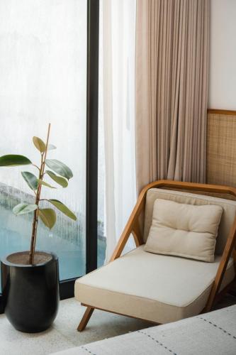 a chair and a plant in a room with a window at Tannari Villa Ubud in Ubud