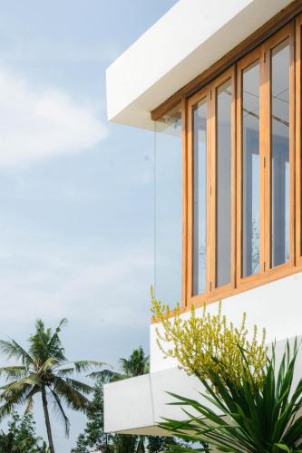 a house with large windows and palm trees at Tannari Villa Ubud in Ubud