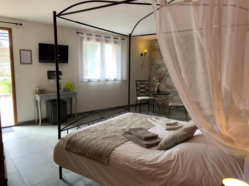 - une chambre avec un lit à baldaquin et des serviettes dans l'établissement La Peireta-Romantique, à Saint Alban Auriolles