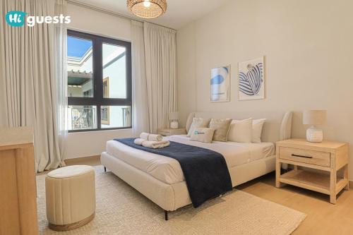 a white bedroom with a bed and a window at HiGuest - Stylish 1BR Apartment in La Mer in Dubai