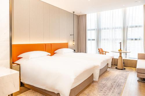 a bedroom with a large white bed and a table at 温州华侨饭店柏宴店 in Wenzhou