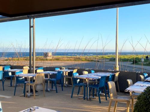 a restaurant with tables and chairs and a view of the water at Logis Hôtel Le Calluna Restaurant La Flottille in Préfailles