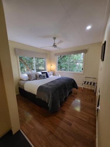 a bedroom with a large bed and two windows at Chilverton Cottages in Ravenshoe