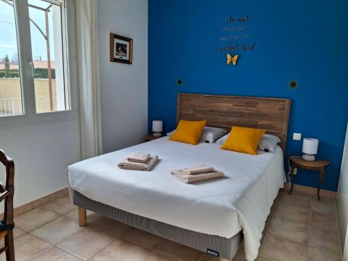 Un dormitorio azul con una cama con toallas. en La Bastide de Laura, en LʼIsle-sur-la-Sorgue