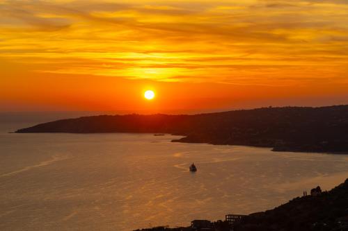 a sunset over the ocean with a boat in the water at Villa Panorama in Lourdhata