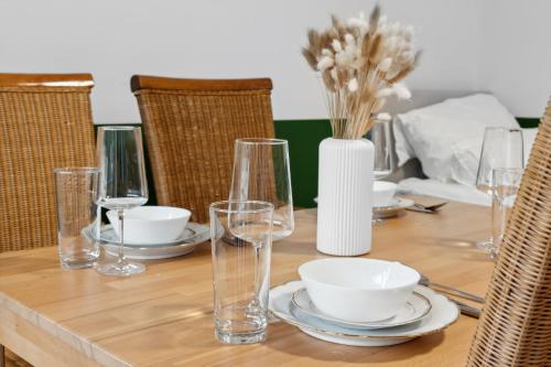 a wooden table with glasses and plates and a vase with flowers at Geschäftsreisetraum 2SZ 5P - Balkon, Waschtrockner in Oberkochen