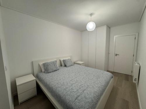 a white bedroom with a bed with two pillows at Vagueira Apartment in Praia da Vagueira