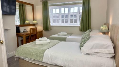 a bedroom with two beds and a window with green curtains at The Cricketers Inn in Winchester