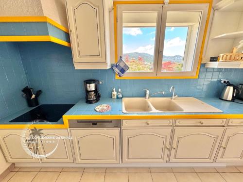 une cuisine avec des armoires blanches, un évier et une fenêtre dans l'établissement Villa La Pialla - Piscine - Plages et Port à pied, à Carqueiranne