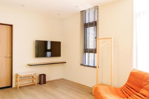 a living room with an orange chair and a tv at Richen Shanshan in Chün-hsin