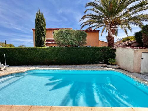 une piscine devant une maison avec un palmier dans l'établissement Villa La Pialla - Piscine - Plages et Port à pied, à Carqueiranne
