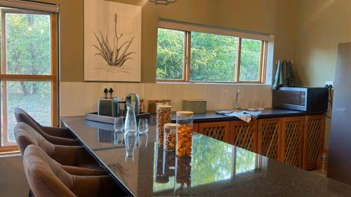 a kitchen with a large counter with chairs and windows at Maroela 1022 in Marloth Park