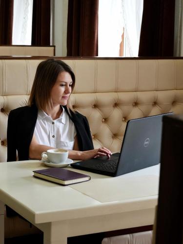 a woman sitting at a table with a laptop computer at Курортний Готель Золота Корона in Truskavets