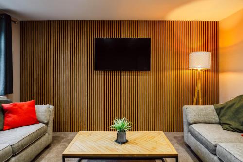 a living room with a couch and a tv on a wall at Dalmarnock Stay in Glasgow
