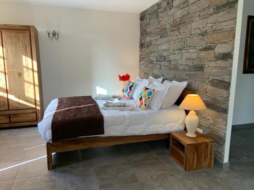 une chambre avec un lit et un mur en pierre dans l'établissement La Peireta-Authentique, à Saint Alban Auriolles