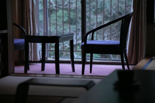 a pair of chairs sitting in front of a window at Shiunso in Hakone