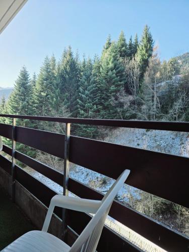 a pair of chairs on a balcony looking out at the trees at L'écrin de Torgon aux Portes du Soleil in Torgon