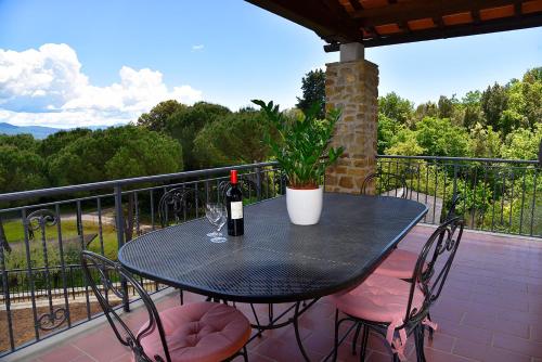 a table with a bottle of wine and chairs on a balcony at Podere Del Griccia in Civitella in Val di Chiana