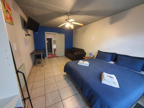 a bedroom with a blue bed and a ceiling fan at Inn-Finity Empire in Witfield