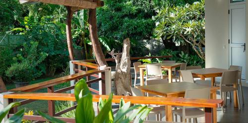 a patio with wooden tables and chairs and trees at Pare LODGE TAHITI in Pirae