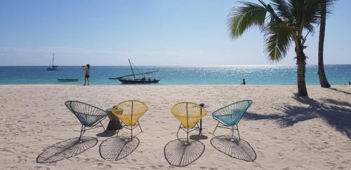 a group of chairs on a beach with the ocean at Secret Garden Villa in Kendwa