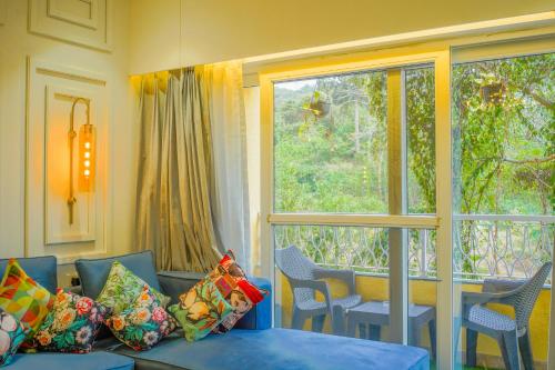 a living room with a couch and a large window at Alaya Stays 1 BHK with Balcony & Pool - Veera Marina in Goa