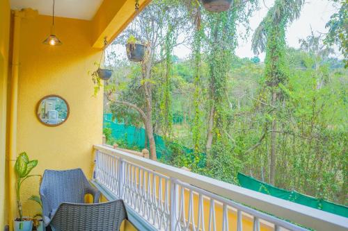 a balcony with two chairs and a large window at Alaya Stays 1 BHK with Balcony & Pool - Veera Marina in Goa