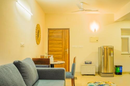 a living room with a couch and a refrigerator at Alaya Stays 1 BHK with Balcony & Pool - Veera Marina in Goa