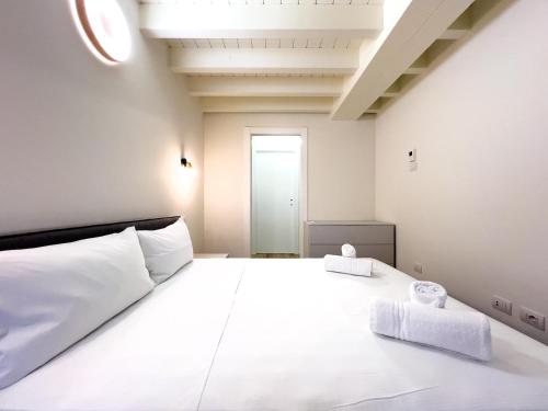 a bedroom with a large white bed with two towels at Bright apartment with terrace and pool in Milan