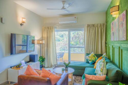 a living room with a green couch and a window at Alaya Stays 1 BHK with Balcony & Pool - Veera Marina in Goa