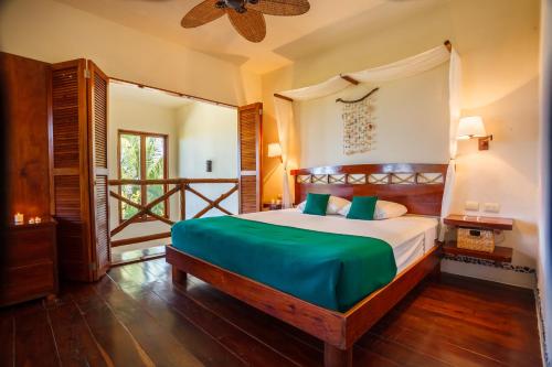 a bedroom with a bed with green sheets and a window at Villas HM Paraiso del Mar in Holbox Island