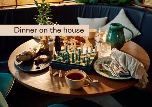 a wooden table with a chess board and dishes of food at Home Hotel Park in Halden