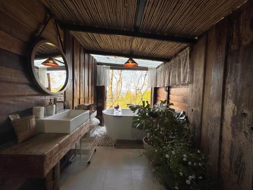 a bathroom with a tub and a sink and a mirror at Ma Family Coffee Farm ไร่กาแฟครอบครัวมะ in Ban Huai Pong Nam Ron
