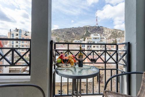 a table with a bowl of fruit and a bottle of wine on a balcony at Downtown Comfort in Tbilisi City