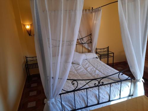 a bedroom with a canopy bed with white curtains at El Horno de Leopoldo in Hueva