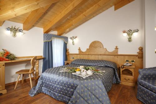 a bedroom with a bed and a table with flowers on it at Hotel Mountain Resort in Commezzadura