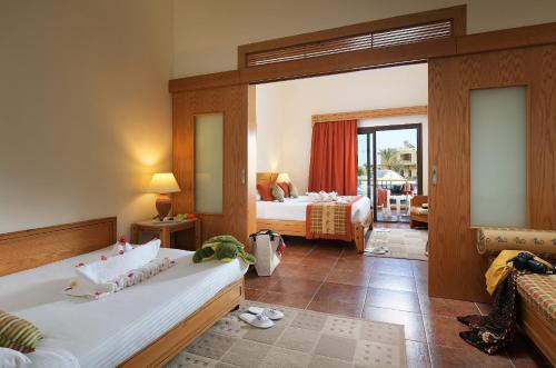 a hotel room with two beds and a balcony at Three Corners Fayrouz Plaza Beach Resort in Port Ghalib