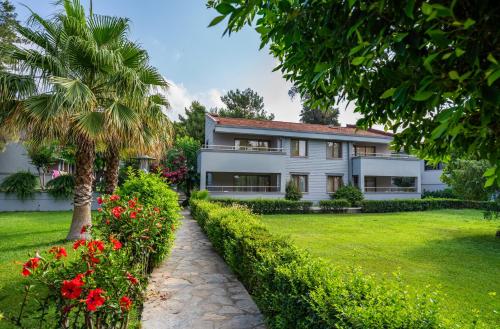 a white house with a palm tree and a garden at Master Family Club in Manavgat