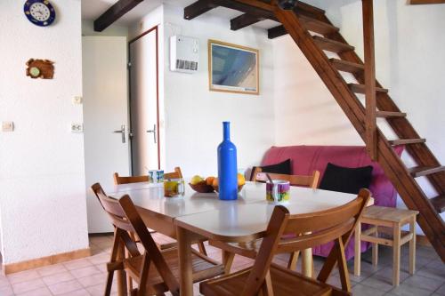- une salle à manger avec une table et une bouteille bleue dans l'établissement Maison Studio mezzanine Gruissan Les Ayguades AY090-003, à Vires