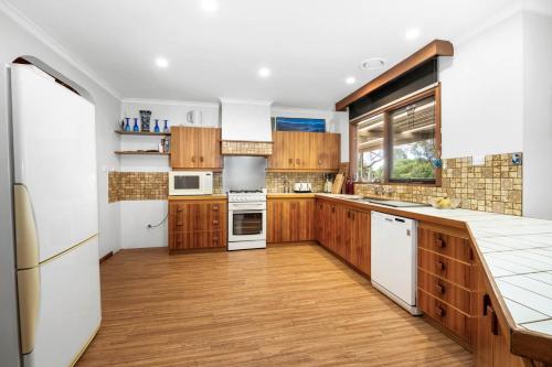 a kitchen with wooden cabinets and white appliances at Bells Beach 5BR Retreat in quiet peaceful spaces- with Hot Tub in Bellbrae