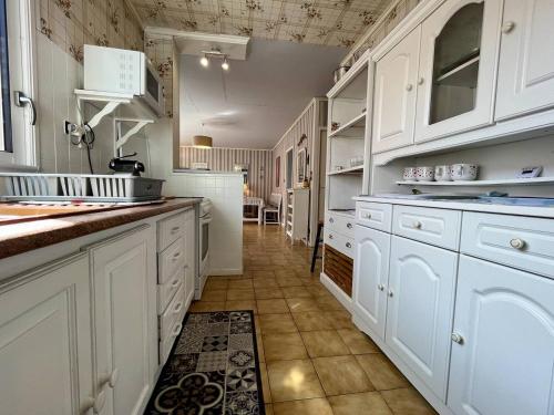une cuisine avec des armoires blanches et un sol carrelé dans l'établissement Maison 3 pièces 5 couchages Saint Pierre d'Oléron SPO000-329, à Saint-Pierre-dʼOléron