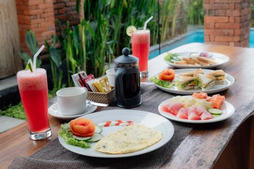 a wooden table topped with plates of food and drinks at Ubud Mayura Private Pool Villa in Ubud