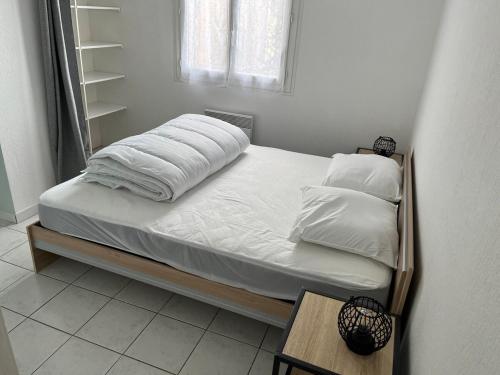 un lit avec des draps blancs et des oreillers dans une chambre dans l'établissement La Bellevue, 15 mn de Toulouse, WIFI, Barbecue, à Labarthe-sur-Lèze